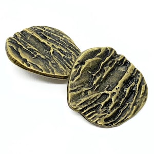 May include: Two antique brass-coloured cabinet knobs with a textured, organic design. The knobs have a weathered appearance, with a mix of dark and light tones, and are set against a white background. The knobs are likely for furniture.