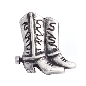 May include: A pair of silver cowboy boots with a spur on one boot. The boots have a western design with intricate details.
