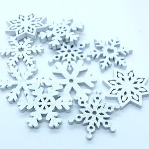 May include: A collection of white wooden snowflake decorations. The snowflakes are of various sizes and have intricate designs.