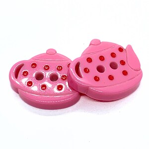 Peut inclure: Deux boutons roses en forme de théière avec des points rouges. Les boutons ont une finition brillante et sont conçus avec une anse, un bec et un couvercle. Ces boutons décoratifs sont parfaits pour la couture et les projets d'artisanat.