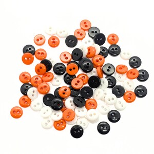 Peut inclure: Un tas de boutons à deux trous assortis en noir, blanc et orange.