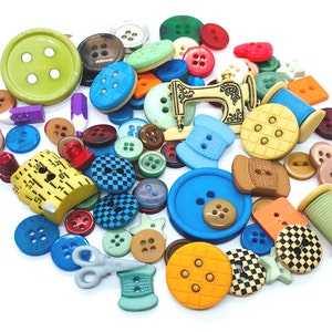 Peut inclure: Une collection de boutons colorés, de bobines de fil et de breloques sur le thème de la couture, dont une machine à coudre miniature. Les boutons sont de formes et de tailles variées, certains présentant des motifs à carreaux.