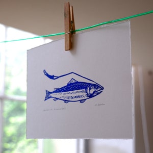 Puede incluir: Una impresión azul y blanca de un pez con el texto "Salmón del Conocimiento" y la firma del artista "R. Goodwin".