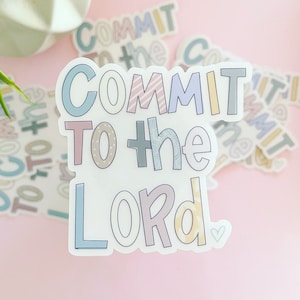 May include: A sticker with the text "COMMIT TO THE LORD" in colorful, patterned letters. The sticker has a white background and a small heart in the bottom right corner.