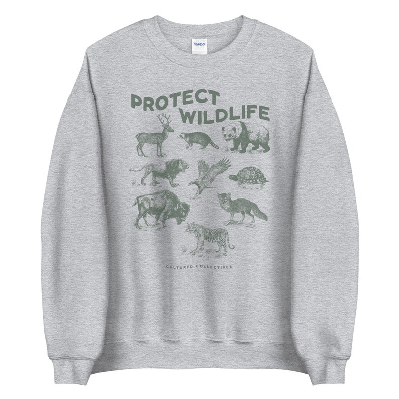 May include: A heather gray sweatshirt with a green graphic that says "PROTECT WILDLIFE." The graphic features illustrations of various animals, including a deer, raccoon, panda, bear, lion, eagle, turtle, bison, fox, and tiger. The words "CULTURED COLLECTIVES" are at the bottom.