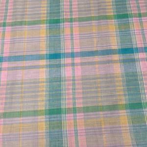May include: A pink, blue, green, and yellow plaid fabric with a woven texture.
