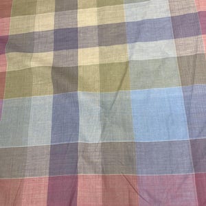 May include: A fabric with a checkered pattern in shades of red, blue, green, and beige. The fabric is woven with a subtle texture.