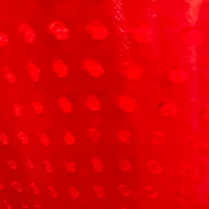 May include: A close-up of a red surface with a repeating pattern of small, white dots.