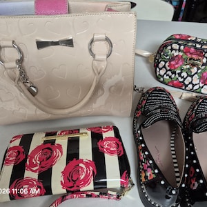 May include: A beige patent leather handbag with an embossed heart pattern, a small floral print cosmetic bag, a black and white striped wallet with red roses, and a pair of black loafers with rhinestone embellishments and floral accents.