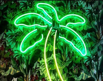 Könnte beinhalten: Ein neongrünes Palmenbaum-Schild mit weißem Umriss, das vor einem Hintergrund aus üppigem grünem Laub hängt.