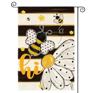 May include: A rectangular garden flag featuring horizontal black and beige stripes, decorated with yellow and black bees, small yellow flowers, and a large white daisy. The word "hi" is printed in a bold, yellow, cursive script on the left side.