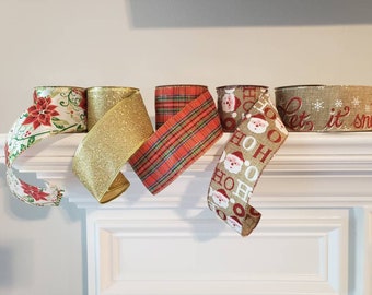 May include: Four rolls of Christmas ribbon with different patterns. One roll is gold glitter, one is red and green plaid, one is white with red Santa faces and the words "Ho Ho Ho", and one is beige with red snowflakes and the words "Let it snow".