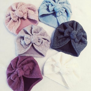 May include: Six different colored turban headbands with a knotted bow on top. The colors are light blue, pink, light gray, dark gray, white, and burgundy.