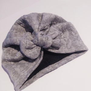 May include: Gray quilted turban with a knotted bow on top.