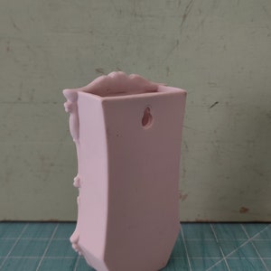 Puede incluir: Un macetero de pared de cer&aacute;mica rosa con un dise&ntilde;o decorativo y un agujero para colgar.