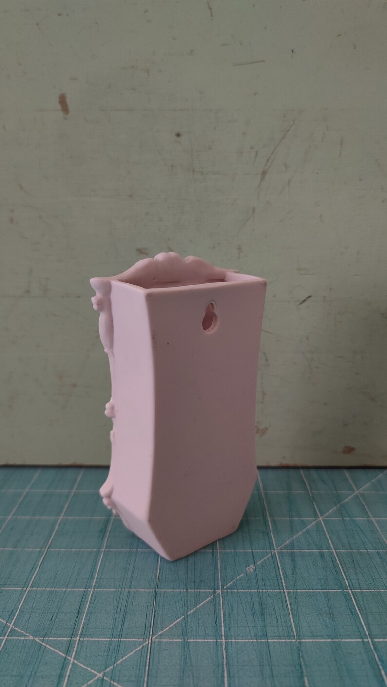 Puede incluir: Un macetero de pared de cer&aacute;mica rosa con un dise&ntilde;o decorativo y un agujero para colgar.