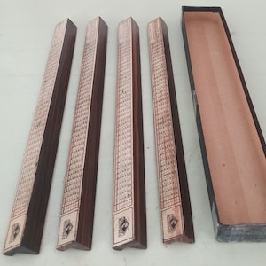 May include: Four wooden game pieces with intricate designs and a black box. The pieces are rectangular with a triangular end and have a brown finish.