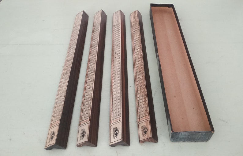 May include: Four wooden game pieces with intricate designs and a black box. The pieces are rectangular with a triangular end and have a brown finish.