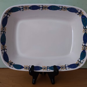 Può includere: Piatto da portata rettangolare in ceramica bianca con un motivo di pesci blu e dorati attorno al bordo.