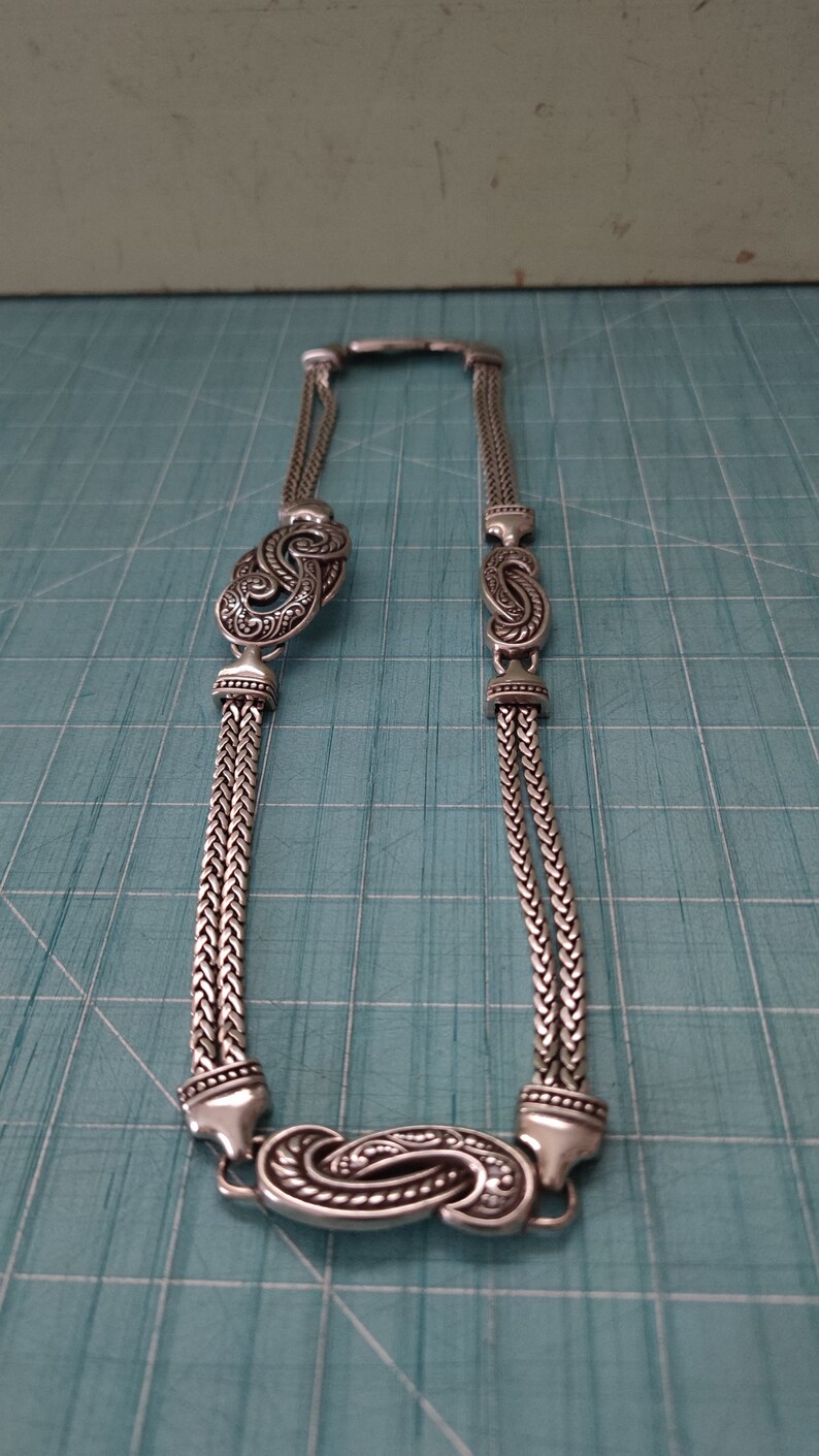 Peut inclure: Un collier en cha&icirc;ne argent avec deux pendentifs orn&eacute;s en argent en forme de paisley.