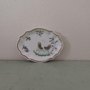 May include: A white oval porcelain dish with a gold rim and a green and gold floral design featuring two birds.