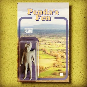 May include: A gray devil figurine in a clear plastic case, set against a backdrop of a scenic landscape. The packaging reads "Penda's Fen" and "I AM MUD AND FLAME" in a retro font, evoking a vintage toy aesthetic.