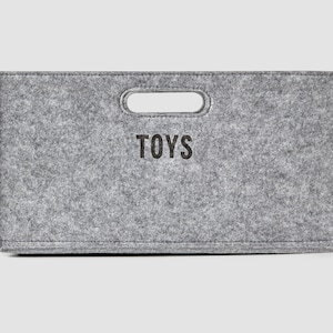 May include: A gray felt storage bin with a cut-out handle and the word "TOYS" printed on the front.