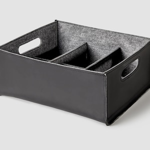 May include: Black felt-lined storage box with three compartments and two handles. The box is made of a faux leather material.