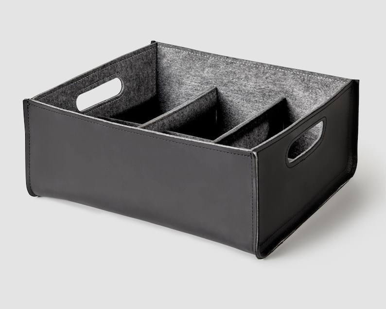 May include: Black felt-lined storage box with three compartments and two handles. The box is made of a faux leather material.