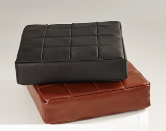 Könnte beinhalten: Zwei quadratische Kissen, eines schwarz und eines braun, mit einem gesteppten Design. Die Kissen sind aus Leder und haben eine weiche, komfortable Haptik.