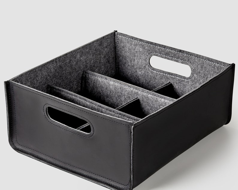 May include: Black leather storage box with a gray felt interior divided into three compartments. The box has two cut-out handles on the sides.