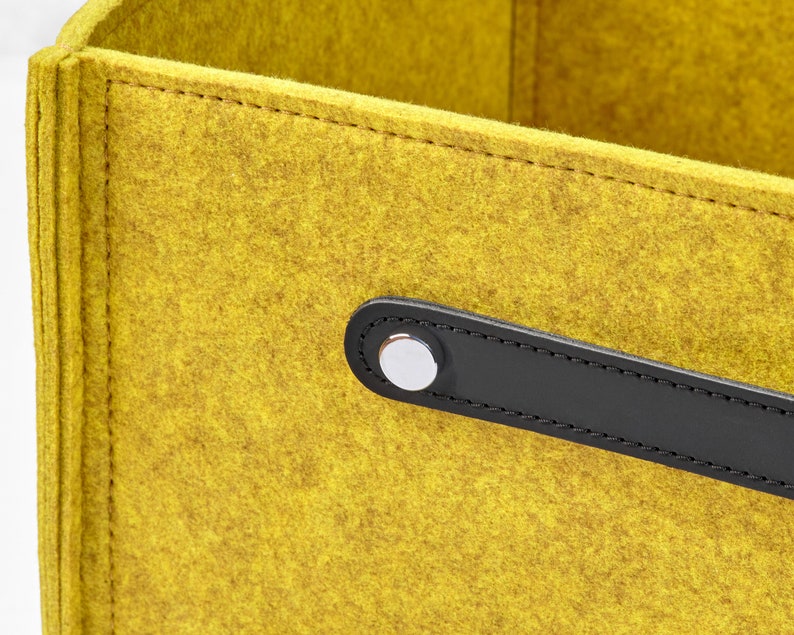 May include: A yellow felt storage box with a black leather handle and a silver metal button.