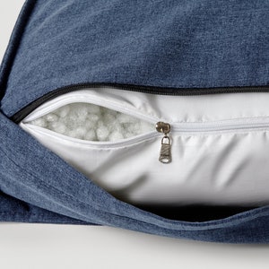 May include: A blue zippered pillow cover with a white zipper and white filling visible inside.