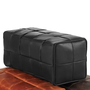 May include: Black leather ottoman with a quilted design. The ottoman is rectangular and has a square top.