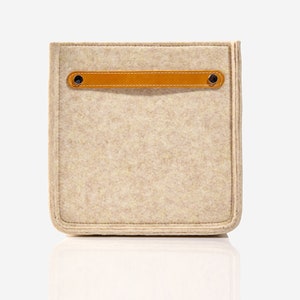 May include: A beige felt storage box with a brown leather handle and two metal rivets. The box has a stitched edge.