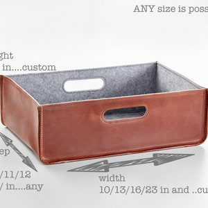 May include: A brown leather storage box with a gray felt lining. The box has two handles on the top and one on the front. The box is 6 to 8 inches high, 10 to 23 inches wide, and 10 to 16 inches deep.  ANY size is possible.