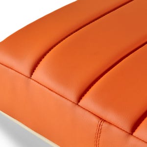 May include: Orange quilted cushion with a white border. The cushion is made of a soft, textured fabric.