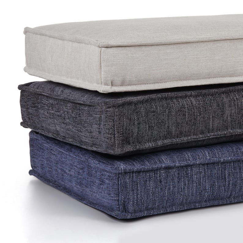 May include: Three rectangular cushions stacked on top of each other. The top cushion is light gray, the middle cushion is dark gray, and the bottom cushion is navy blue. Each cushion has a stitched border.