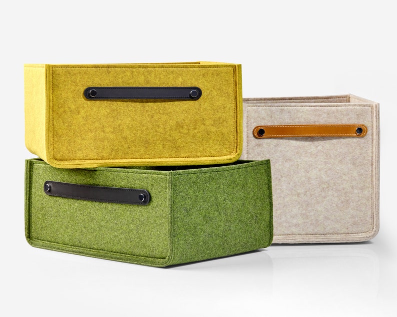 May include: Three felt storage boxes with leather handles. The top box is yellow, the middle box is green, and the bottom box is beige.