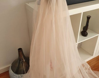 May include: A long, ivory-colored tulle veil with a single layer. The veil is gathered at the top and hangs down to the floor.