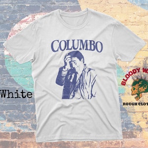 May include: White t-shirt with a blue and white image of a man with the text "COLUMBO" printed in blue above the image. The text "BLOODY WASABI ROUGH CLOTHING" is printed in red and black on the bottom right corner of the shirt.