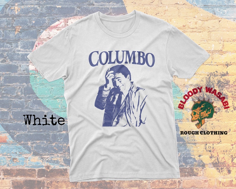 May include: White t-shirt with a blue and white image of a man with the text "COLUMBO" printed in blue above the image. The text "BLOODY WASABI ROUGH CLOTHING" is printed in red and black on the bottom right corner of the shirt.