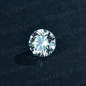 Puede incluir: Una piedra preciosa redonda y transparente de diamante con muchas facetas, sobre un fondo negro.