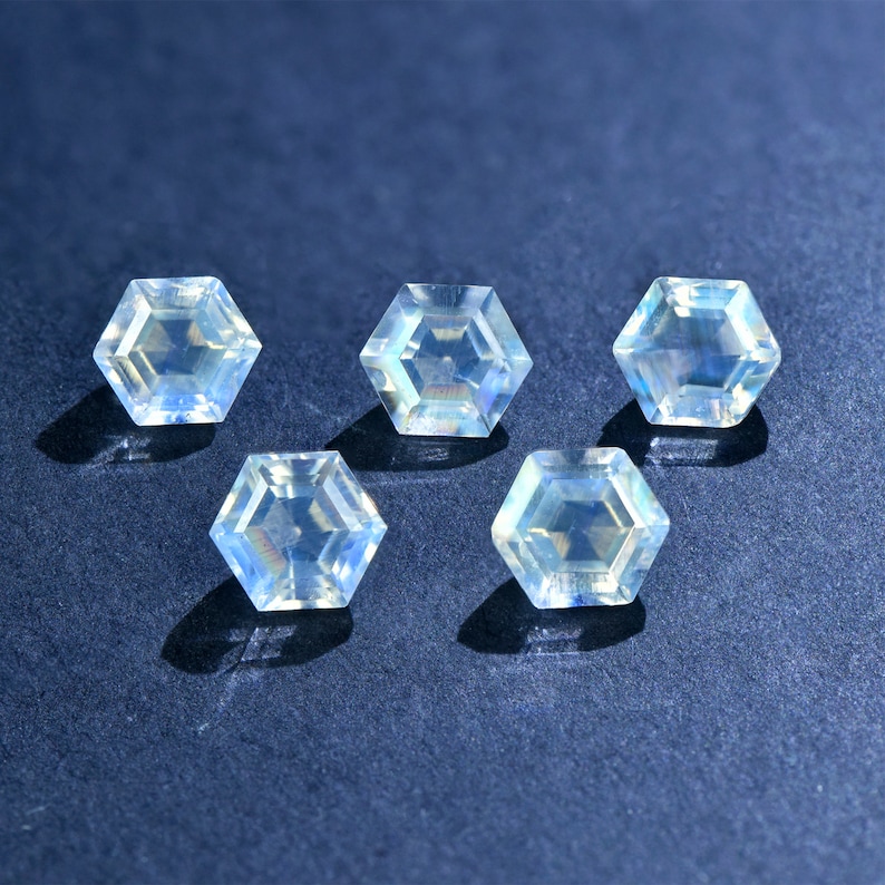May include: Six hexagonal iridescent gemstones with a light blue and white color.