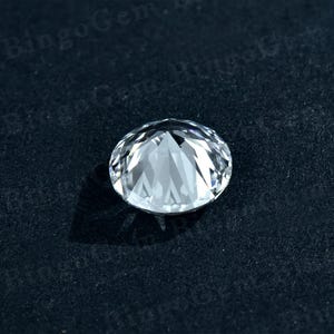 Puede incluir: Una piedra preciosa redonda transparente con muchas facetas, sobre un fondo negro.