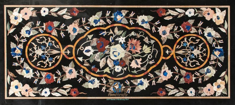May include: A rectangular black marble tabletop with a floral mosaic design. The mosaic features flowers in shades of white, pink, red, and blue, with green leaves and a gold border. The design is symmetrical and intricate, showcasing detailed craftsmanship.