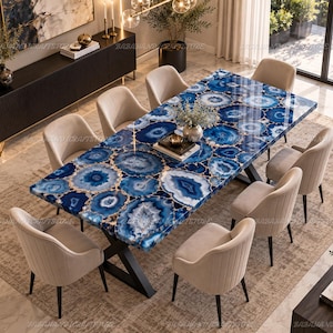 May include: A rectangular dining table featuring a polished surface made of blue agate stone slices with white and dark blue concentric patterns, supported by a black metal X-shaped base, surrounded by eight beige upholstered dining chairs.
