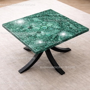 May include: Square green malachite table with a black base. The tabletop features a unique pattern of swirling green and white, supported by a black, curved base. The table is a decorative piece for a living room or office.