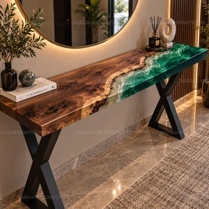 Può includere: Un lungo tavolo console caratterizzato da una lastra di legno di noce naturale con bordo vivo abbinata a una sezione in resina verde vibrante che imita le onde dell'oceano con dettagli in schiuma bianca. Il tavolo ha due gambe in metallo nero a X.