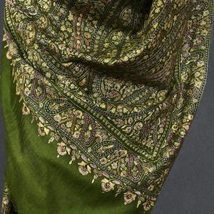 May include: A green shawl with a paisley pattern and gold embroidery. The shawl is made of a soft, luxurious fabric and is perfect for adding a touch of elegance to any outfit.